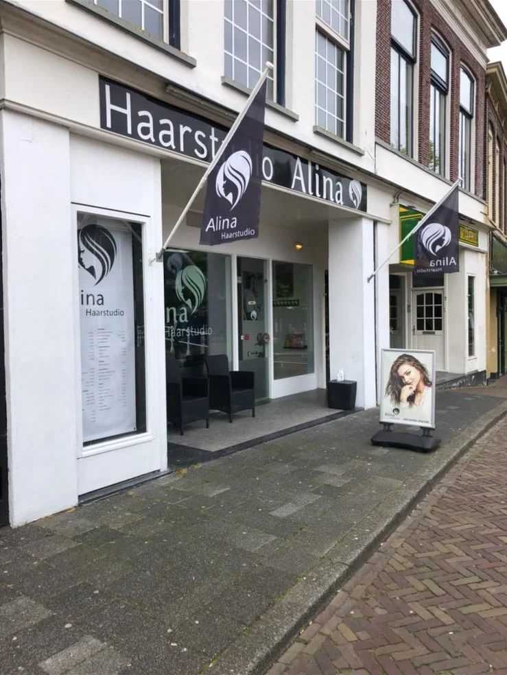 Gevel van Haarstudio Alina met vlaggen en stoepbord