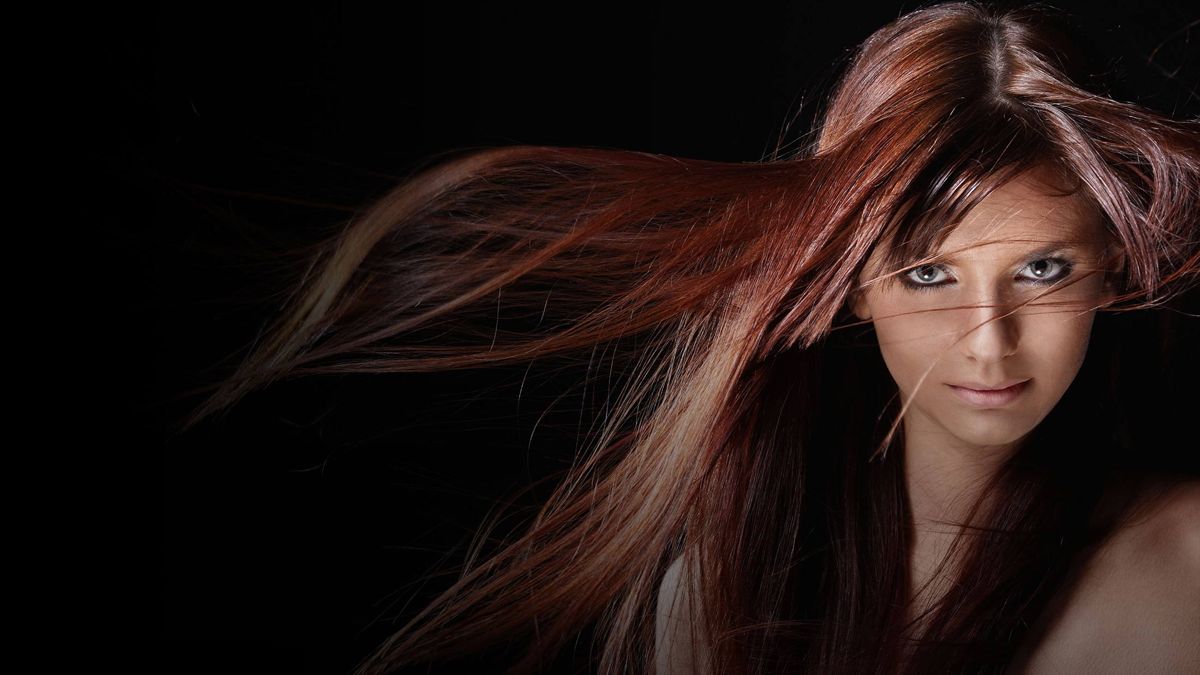 Model met lang roodbruin haar tegen een zwarte achtergrond